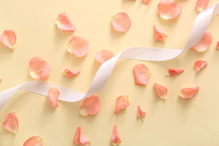 Beautiful rose petals with ribbon on beige backgroundの写真素材
