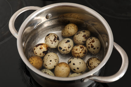 Stainless steel cooking pot with boiling quail eggs on stove, closeupの写真素材