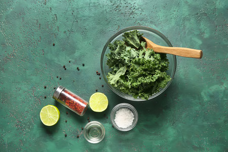 Glass bowl with fresh leaves of kale cabbage and different spices on green backgroundの写真素材