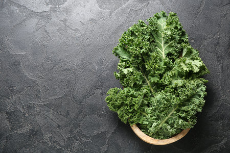 Wooden bowl with fresh leaves of kale cabbage on black backgroundの写真素材