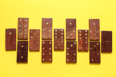 Wooden dominos blocks on yellow backgroundの写真素材