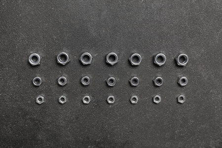 Arrangement of chrome nuts on gray grunge background