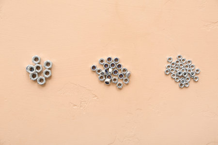 Piles of different chrome nuts on beige backgroundの写真素材