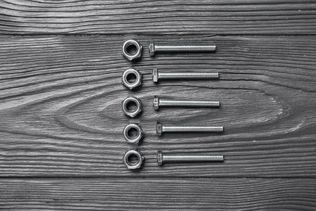 Tap bolts and chrome nuts on gray wooden backgroundの写真素材
