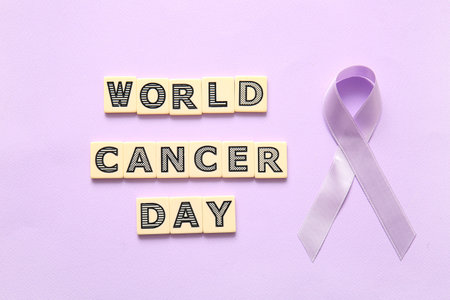 Text WORLD CANCER DAY with lilac awareness ribbon on color backgroundの写真素材