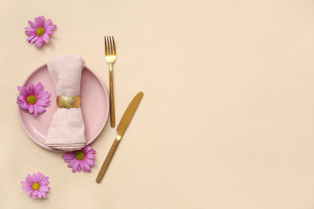 Stylish table setting with beautiful chrysanthemum flowers on beige backgroundの写真素材