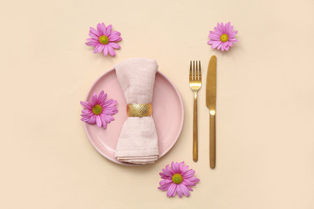 Stylish table setting with beautiful chrysanthemum flowers on beige backgroundの写真素材