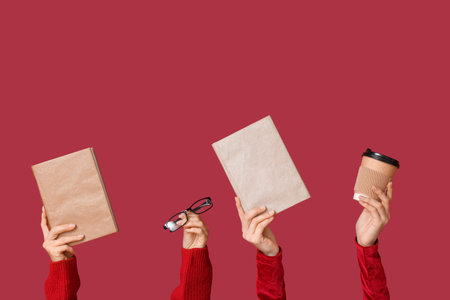 Female hands with eyeglasses, books and cup of coffee on red backgroundの写真素材