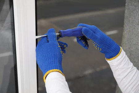 Male worker repairing window with screwdriver in room, closeupの写真素材