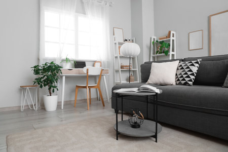Interior of light living room with black sofa, lamp and workplaceの写真素材