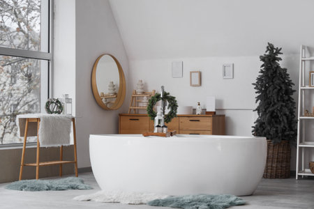 Interior of light bathroom with bathtub, Christmas tree and wreathの写真素材