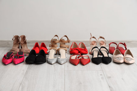 Different women's shoes near light wall in room