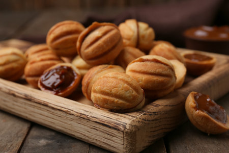 Cutting board of sweet walnut shaped cookies with boiled condensed milk on wooden background, closeupの写真素材