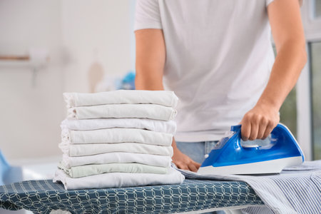 Handsome young man ironing clean clothes at home, closeupの写真素材