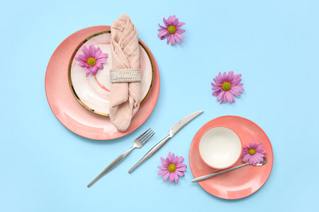 Stylish table setting with beautiful chrysanthemum flowers on blue backgroundの写真素材