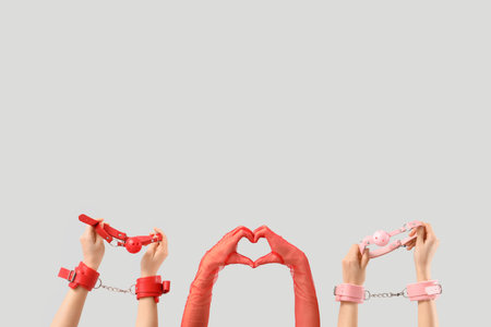 Female hands with sex toys making heart gesture on light background. Valentine's Day celebrationの写真素材