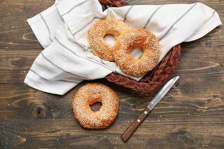 Wicker basket of tasty bagels with sesame seeds on wooden backgroundの写真素材