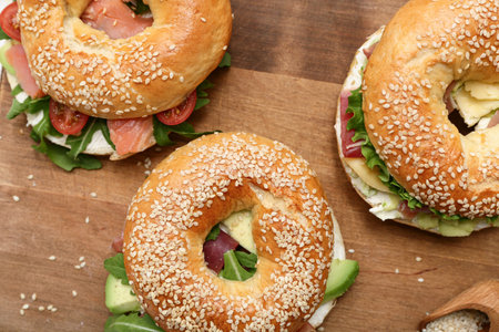 Tasty bagel sandwiches with ingredients on wooden backgroundの写真素材
