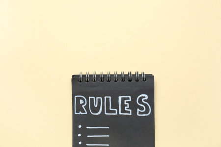 Notebook with blank list of rules on beige background