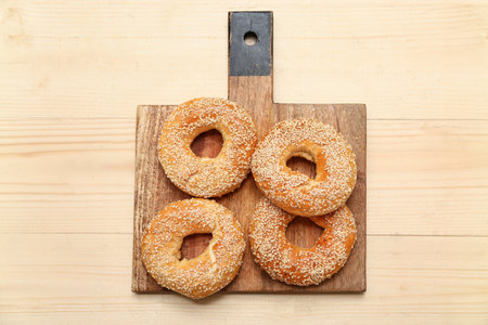 Cutting board of tasty bagels with sesame seeds on wooden backgroundの写真素材
