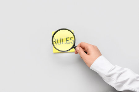 Woman magnifying sticky note with word RULES on light backgroundの写真素材