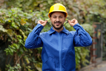 Male builder putting in earplugs outdoors