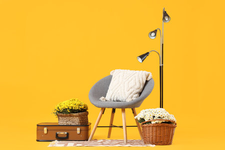 Gray armchair, lamp and chrysanthemum flower on yellow backgroundの写真素材