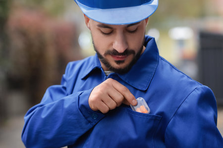 Male builder taking earplugs from pocket outdoors, closeupの写真素材