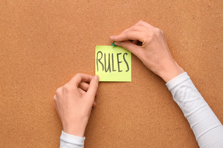 Woman pinning paper with word RULES on boardの写真素材