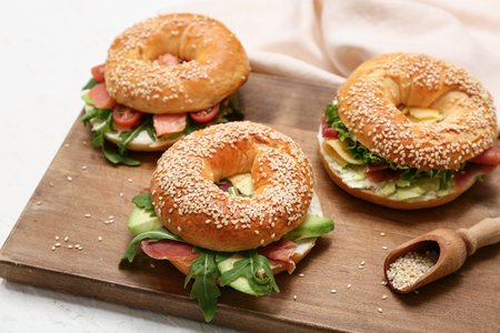 Wooden board of tasty bagel sandwiches with ingredients on white background, closeupの写真素材