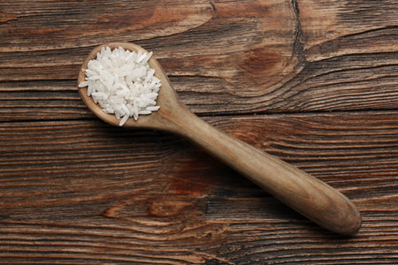 Spoon with raw rice on wooden backgroundの写真素材