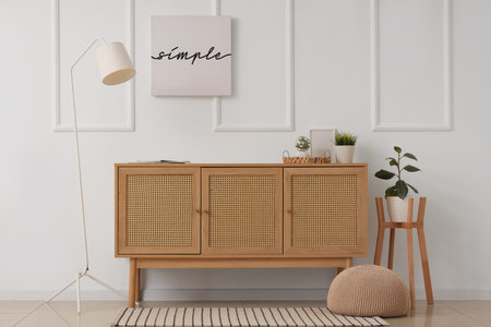 Interior of light room with wooden commode, lamp and posterの写真素材