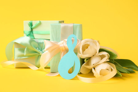 Paper figure 8 with gift boxes and tulips on yellow background. Happy Women's Day