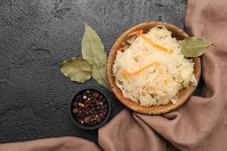 Bowl of tasty sauerkraut with bay leaves and peppercorns on black background. Top viewの写真素材