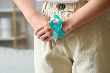 Young woman with turquoise ribbon at home, closeup. Cervical Health Awareness Monthの写真素材
