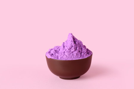 Bowl of violet powder pigment on pink backgroundの写真素材