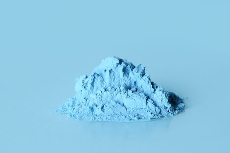 Heap of powder pigment on blue background
