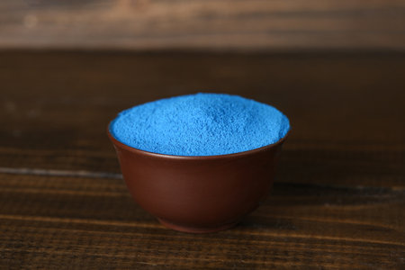 Bowl of blue powder pigment on wooden table, closeupの写真素材