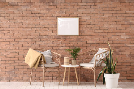 Interior of living room with wicker armchairs, table and blank frameの写真素材