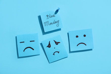 Paper sheets with drawn sad faces and text BLUE MONDAYの写真素材