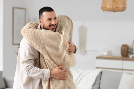 Young man hugging his mother at homeの写真素材