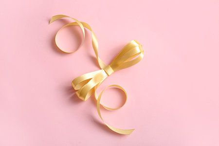 Satin ribbon with bow on pink background