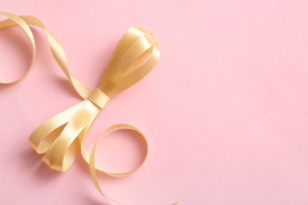 Satin ribbon with bow on pink backgroundの写真素材