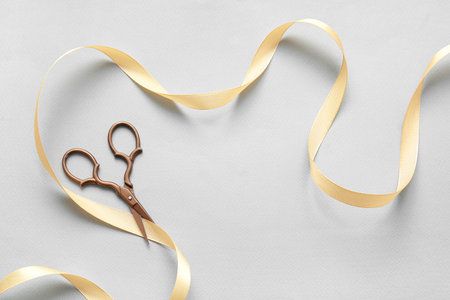 Beautiful satin ribbon with scissors on gray backgroundの写真素材