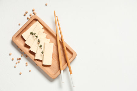 Tray with slices of tasty tofu cheese, chopsticks and chickpeas on white backgroundの写真素材