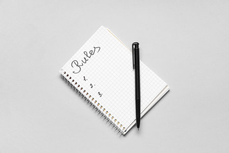Notebook with blank list of rules on light background