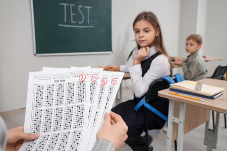 Teacher with checked answer sheets in classroom, closeupの写真素材