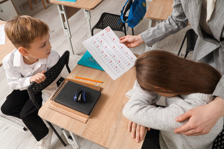 Upset schoolgirl and teacher with results of test in classroomの写真素材