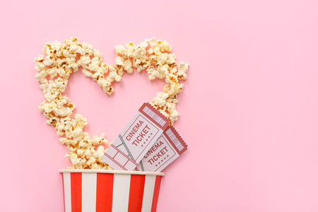 Heart made of popcorn and cinema tickets on pink background. Valentine's Day celebrationの写真素材