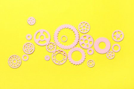 Pink paper gears on yellow background